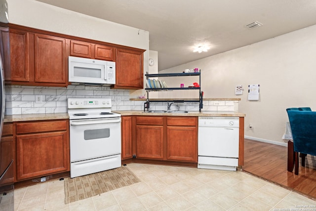 kitchen with tasteful backsplash, sink, light wood-type flooring, and white appliances