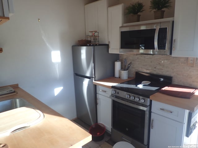 kitchen with stainless steel appliances, white cabinets, and backsplash