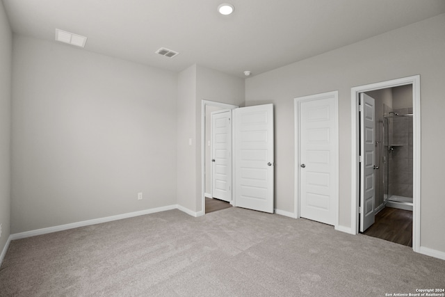 unfurnished bedroom with ensuite bath, dark colored carpet, and a closet