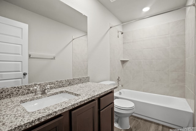 full bathroom with wood-type flooring, tiled shower / bath combo, vanity, and toilet