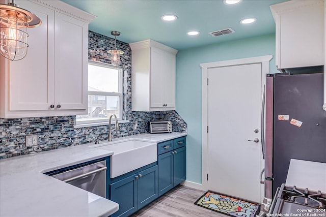 kitchen with sink, white cabinetry, appliances with stainless steel finishes, decorative light fixtures, and blue cabinets