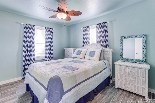 bedroom with multiple windows, wood-type flooring, and ceiling fan