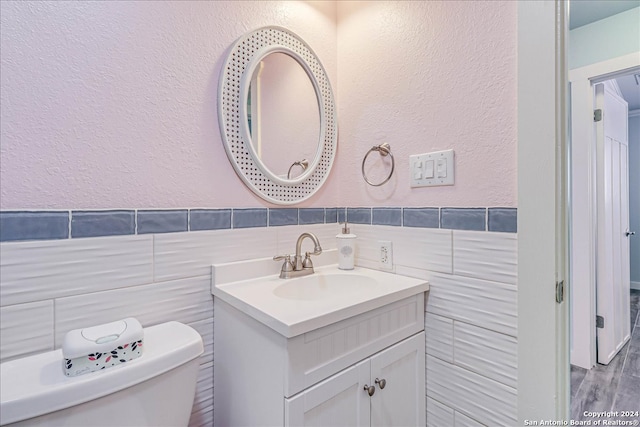 bathroom featuring tile walls, vanity, toilet, and wood-type flooring