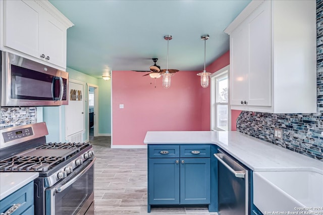 kitchen with white cabinets, light hardwood / wood-style flooring, decorative light fixtures, blue cabinetry, and appliances with stainless steel finishes