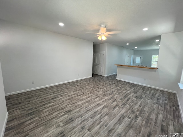 unfurnished living room with ceiling fan and dark wood-type flooring