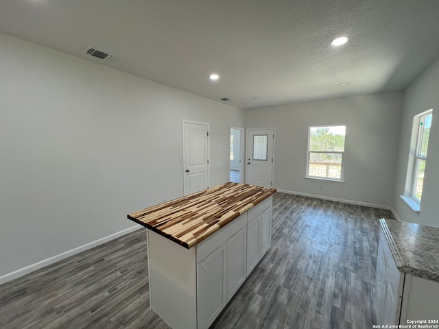 kitchen featuring white cabinets, dark hardwood / wood-style floors, butcher block counters, and a center island