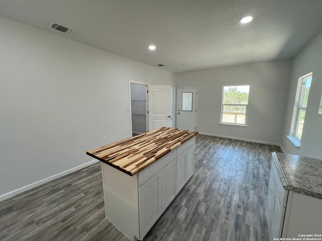 kitchen with white cabinets, dark hardwood / wood-style flooring, wood counters, and a center island