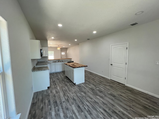 kitchen featuring a textured ceiling, white cabinetry, a center island, and dark hardwood / wood-style flooring