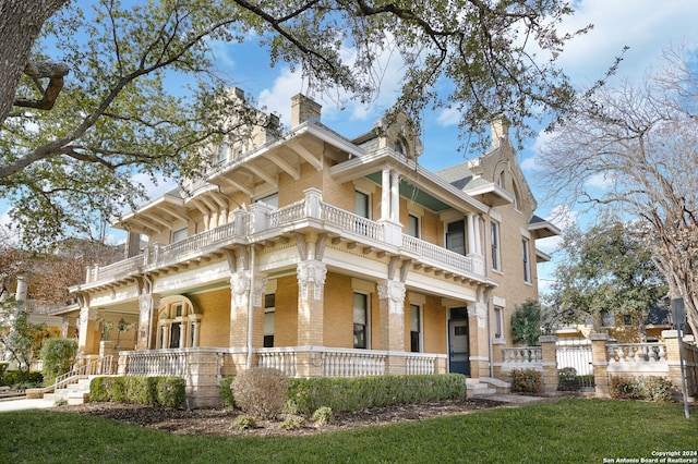 view of front facade with a balcony, a front lawn, and covered porch