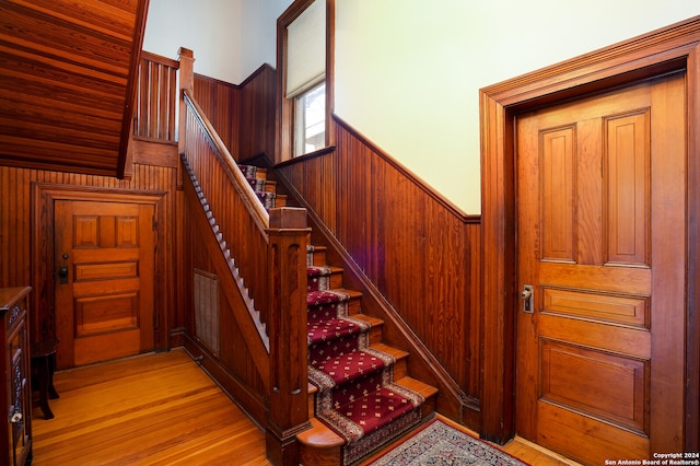 staircase with wooden walls and hardwood / wood-style floors