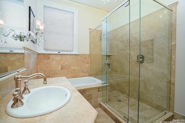 bathroom featuring an inviting chandelier, tile walls, independent shower and bath, and sink