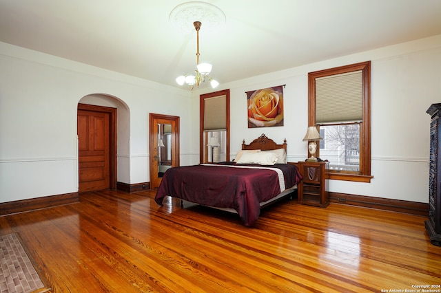 bedroom with wood-type flooring and a notable chandelier