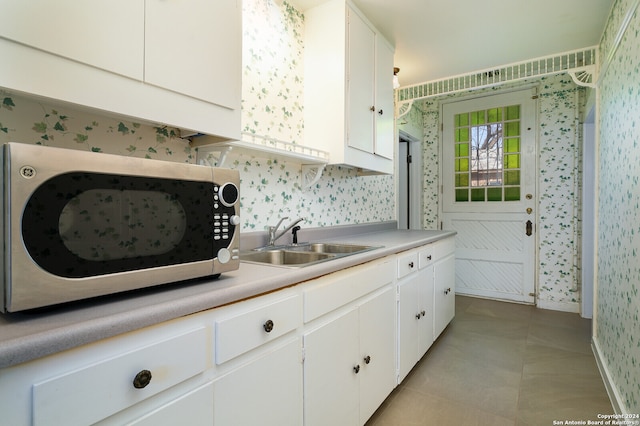 kitchen with light tile patterned floors, sink, and white cabinetry