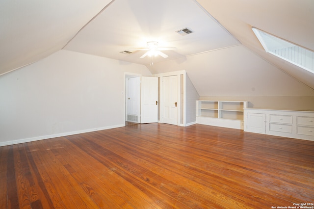 bonus room featuring ceiling fan, hardwood / wood-style flooring, vaulted ceiling with skylight, and built in features