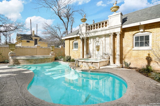 view of swimming pool featuring pool water feature and an in ground hot tub