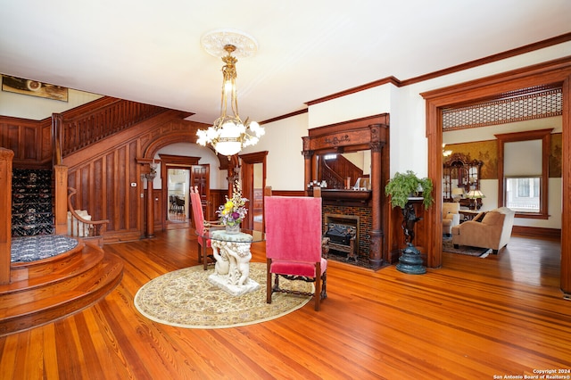 interior space featuring wood-type flooring, a notable chandelier, a fireplace, and crown molding