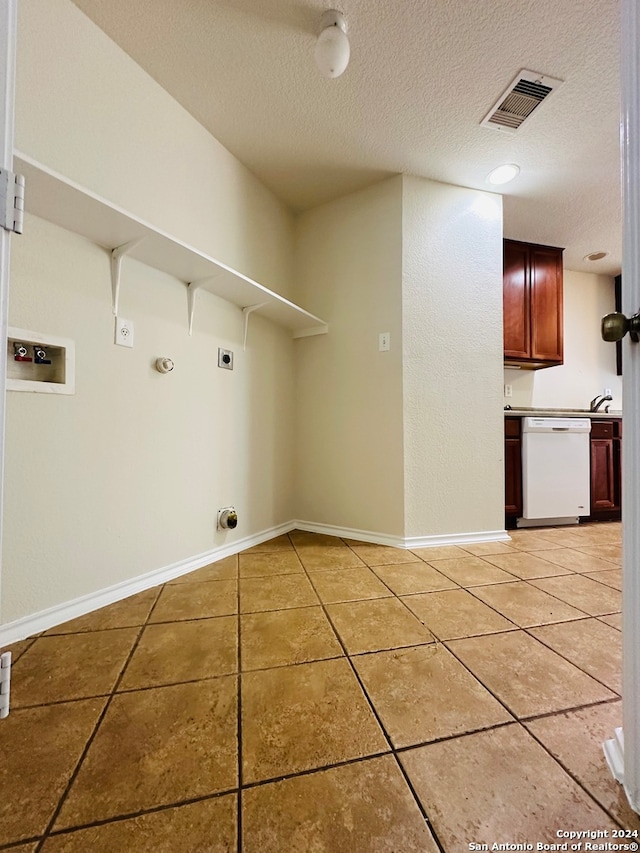 laundry area with hookup for an electric dryer, gas dryer hookup, a textured ceiling, tile patterned floors, and hookup for a washing machine