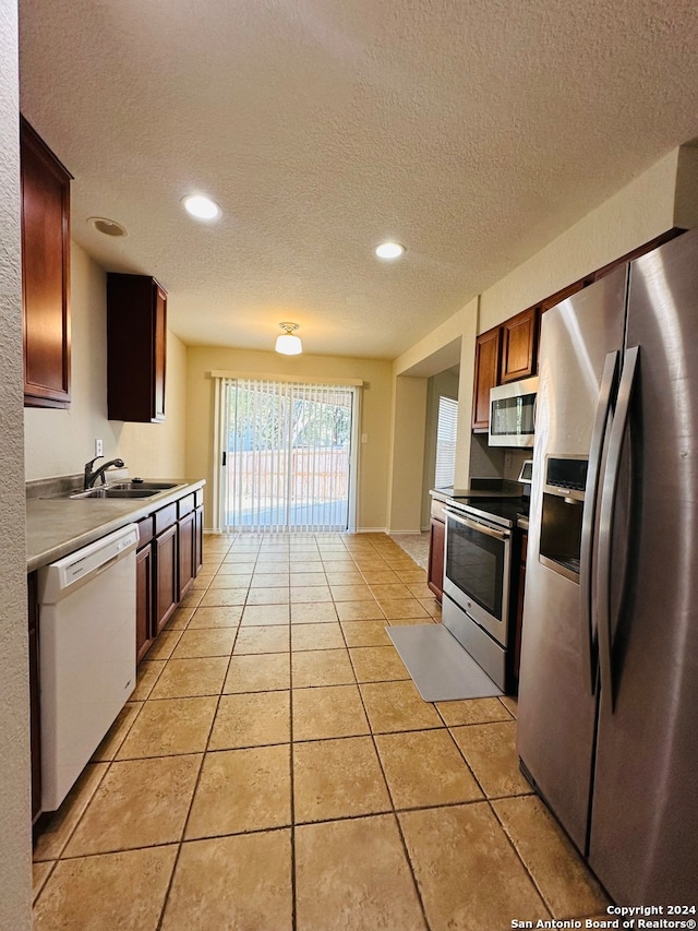 kitchen with light tile patterned floors, a textured ceiling, stainless steel appliances, and sink