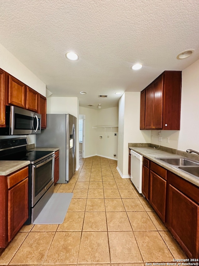 kitchen featuring appliances with stainless steel finishes, a textured ceiling, sink, and light tile patterned floors