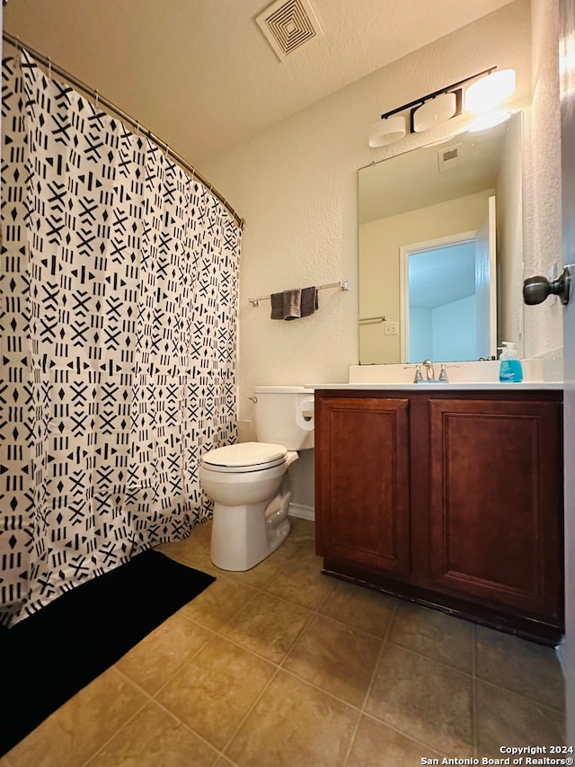 bathroom with vanity, toilet, a textured ceiling, and tile patterned floors