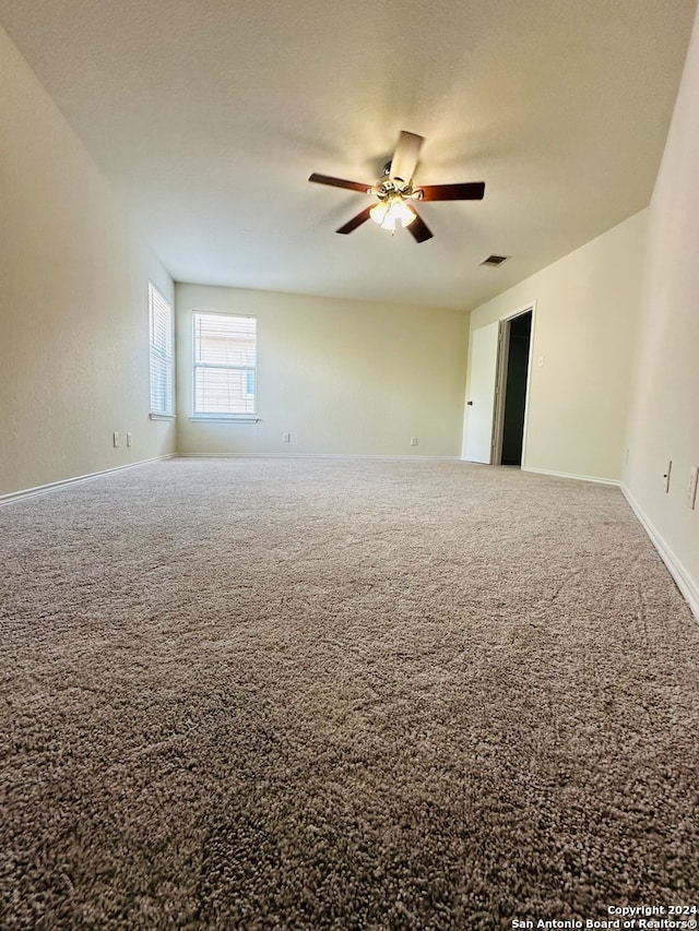 carpeted spare room featuring ceiling fan