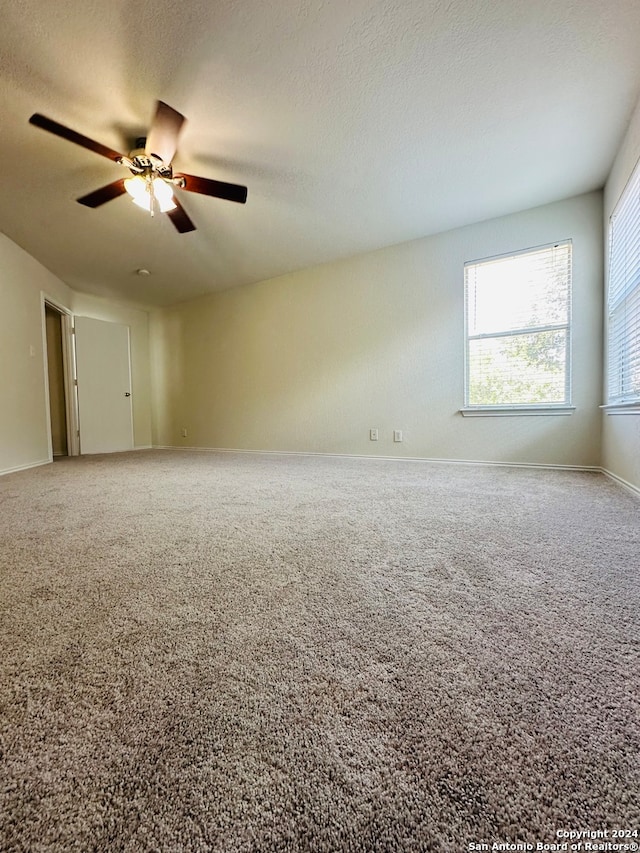 carpeted spare room with ceiling fan and a textured ceiling