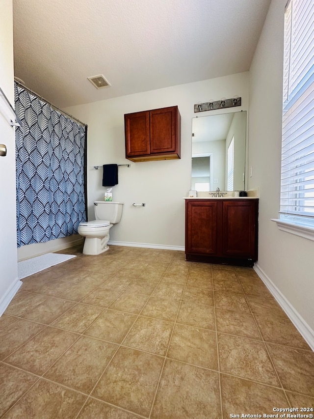 bathroom with tile patterned flooring, walk in shower, vanity, and toilet