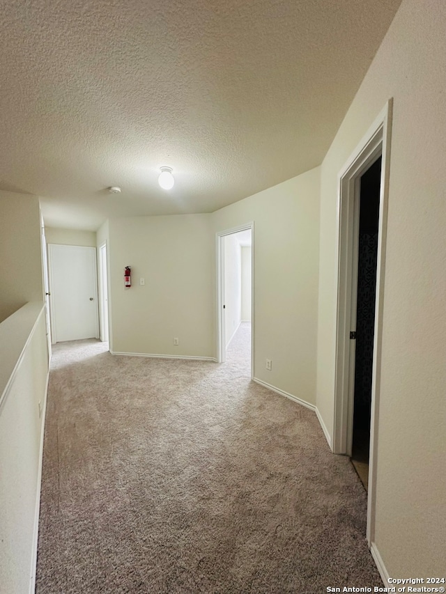 carpeted spare room with a textured ceiling