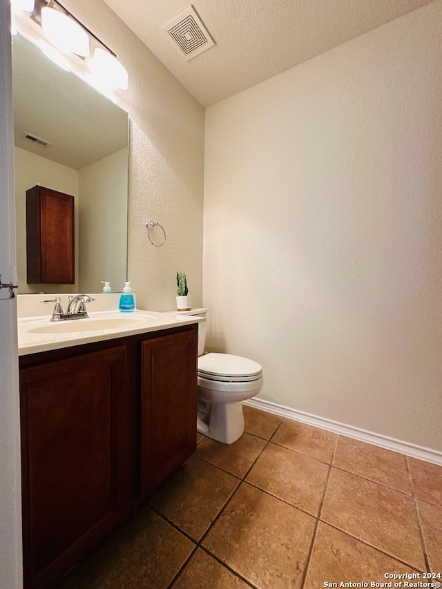 bathroom featuring vanity, toilet, a textured ceiling, and tile patterned floors