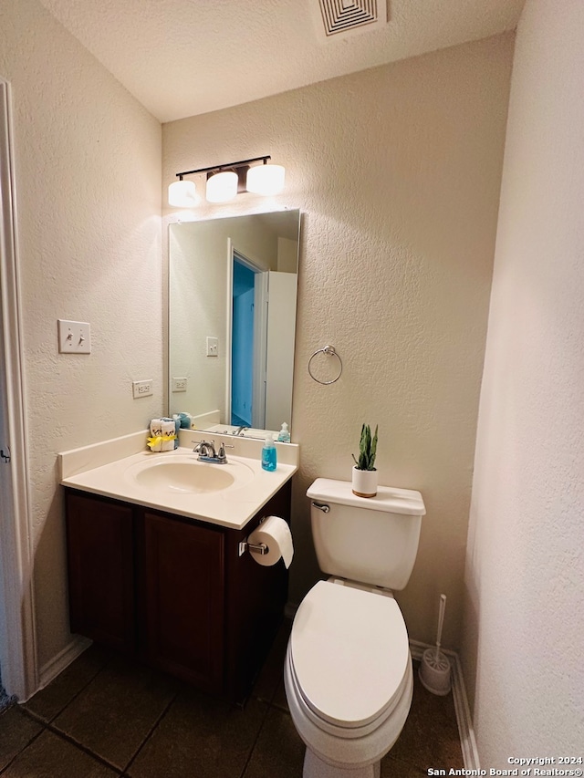 bathroom with a textured ceiling, vanity, toilet, and tile patterned floors