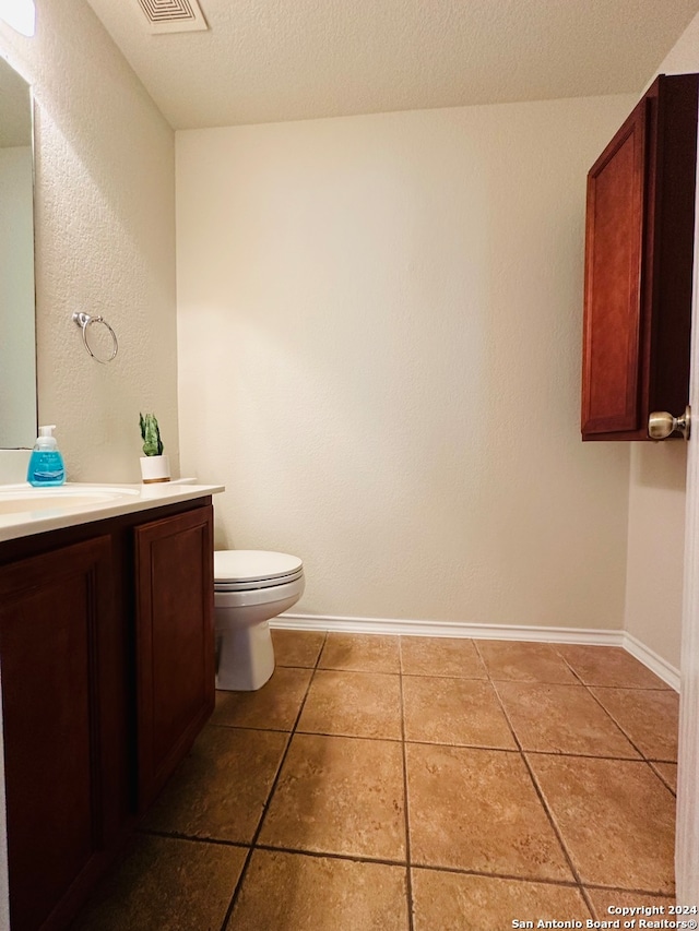 bathroom with tile patterned flooring, a textured ceiling, vanity, and toilet