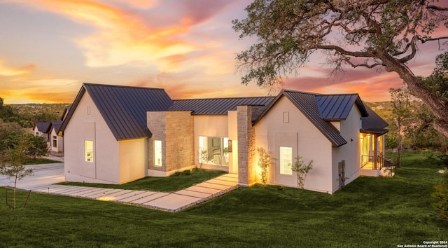 back house at dusk with a lawn