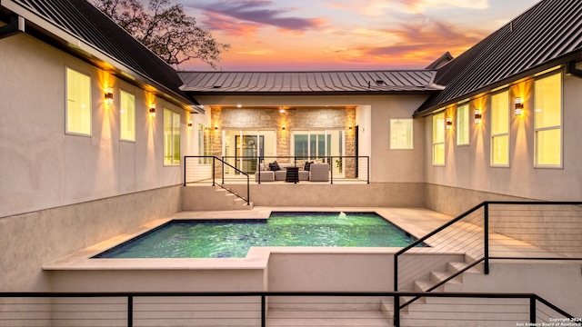 pool at dusk featuring an outdoor living space and a patio area