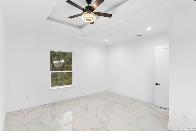 spare room with ceiling fan and a tray ceiling