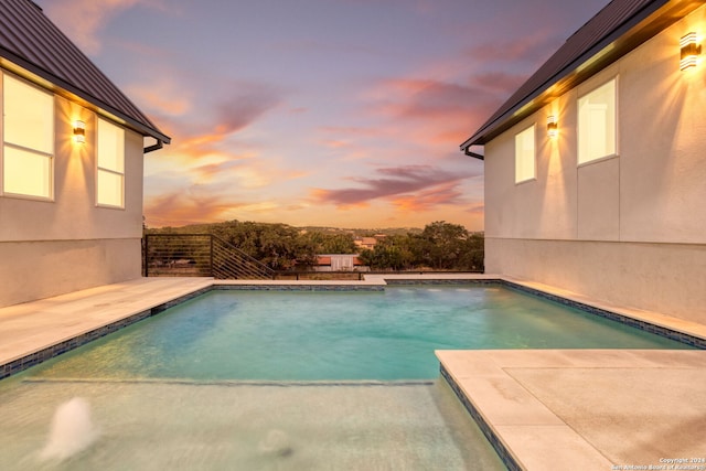 pool at dusk with a patio area