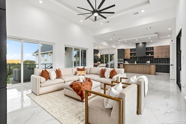 living room featuring a towering ceiling, ceiling fan, and plenty of natural light