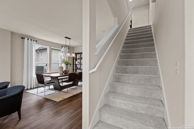 stairs featuring a chandelier and hardwood / wood-style floors