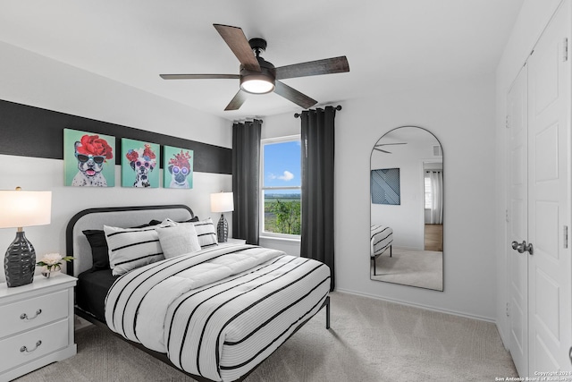 bedroom featuring baseboards, light carpet, a ceiling fan, and a closet