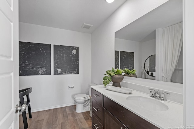 bathroom with wood finished floors, visible vents, toilet, and vanity