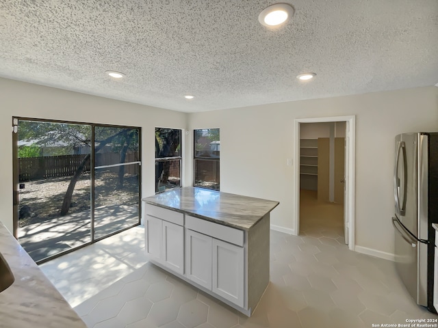 kitchen featuring white cabinets, a textured ceiling, and stainless steel refrigerator