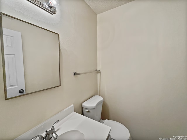 bathroom with a textured ceiling, vanity, and toilet