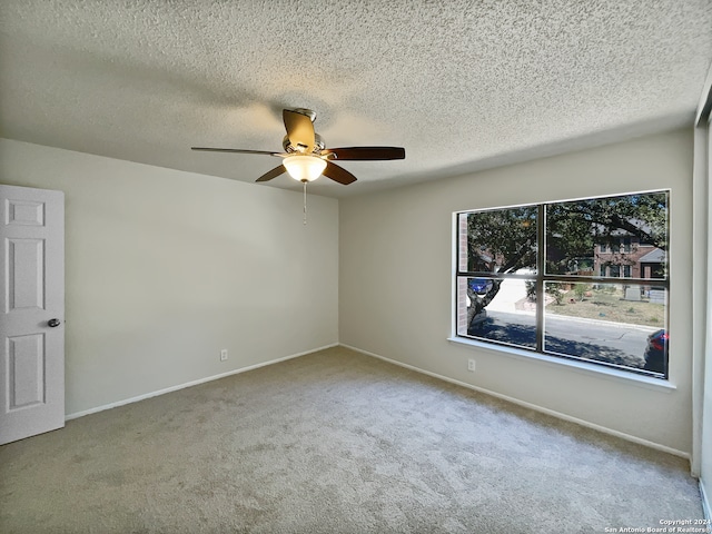 spare room with ceiling fan, a textured ceiling, and carpet