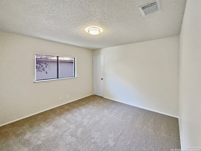 carpeted spare room with a textured ceiling