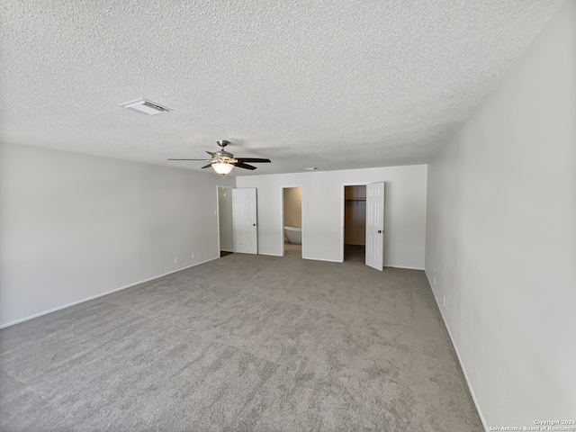 unfurnished bedroom featuring ceiling fan, light colored carpet, and a textured ceiling