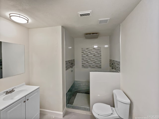 bathroom featuring tiled shower, vanity, a textured ceiling, toilet, and tile patterned floors