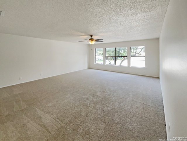 spare room featuring a textured ceiling, carpet flooring, and ceiling fan