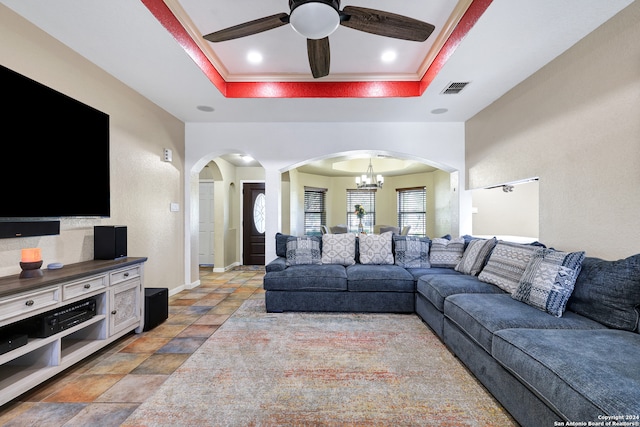 living room featuring ceiling fan with notable chandelier and a tray ceiling