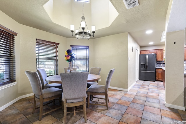 tiled dining area with a textured ceiling and an inviting chandelier