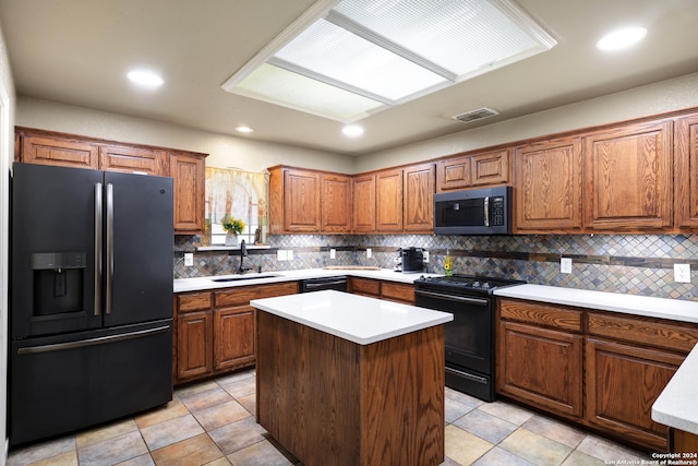 kitchen with decorative backsplash, black appliances, a center island, and sink