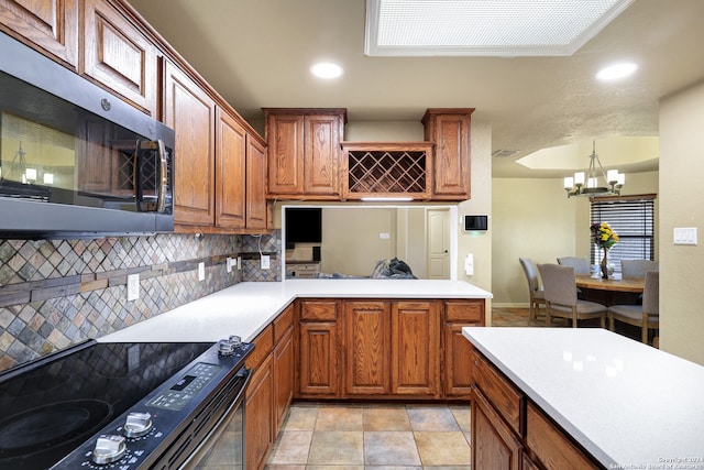 kitchen featuring pendant lighting, black range with electric stovetop, tasteful backsplash, kitchen peninsula, and an inviting chandelier